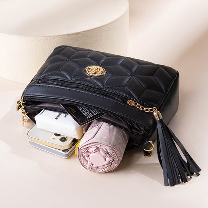 Black quilted handbag with gold accents containing a phone, cards, and a pink umbrella on a light background.